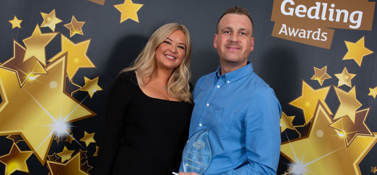 Inspirational Healthy Lifestyle Award Winner, BKS Martial Arts – Warren Benett , stood against the Pride of Gedling black and gold backdrop next to a representative from the category Sponsors.