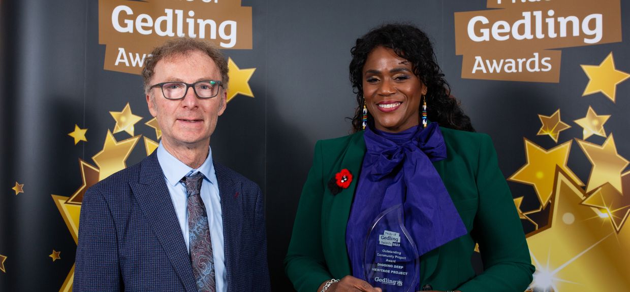 Outstanding Community Project Winner, Norma Gregory, stood against the Pride of Gedling black and gold backdrop next to a representative from the category Sponsors.
